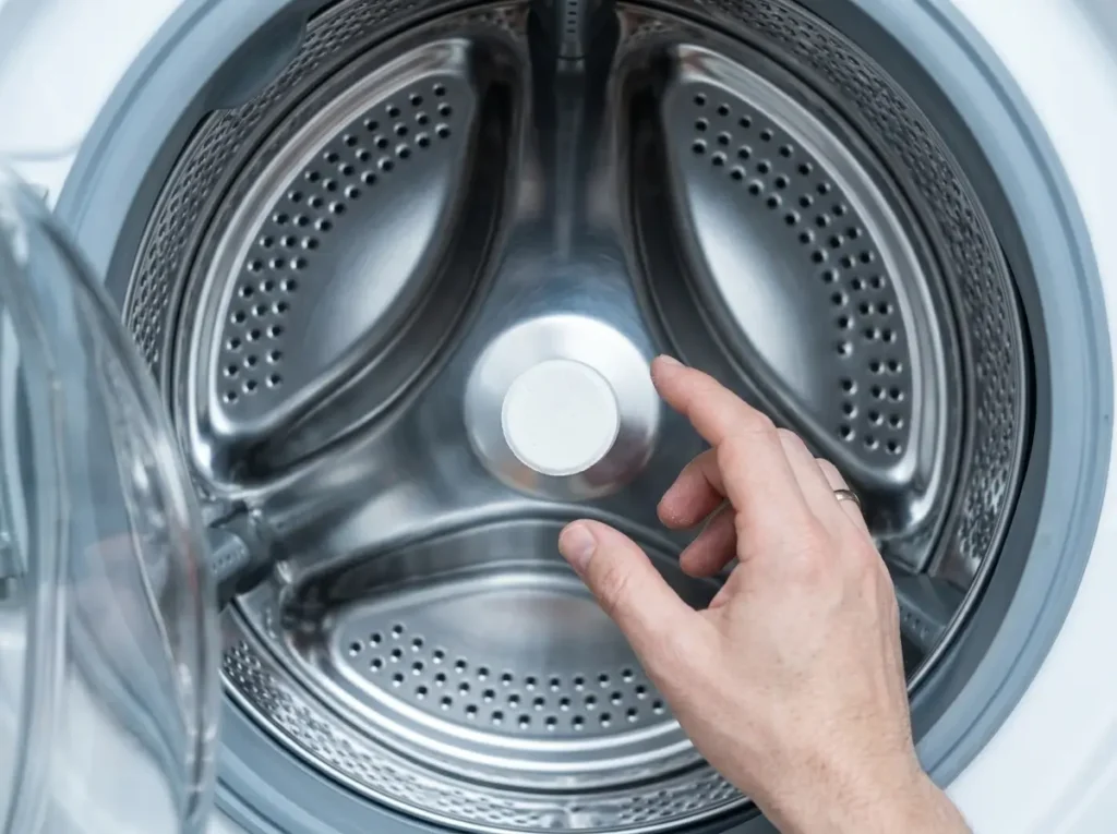Washing machine cleaner tablet placed inside an empty stainless steel washer drum
